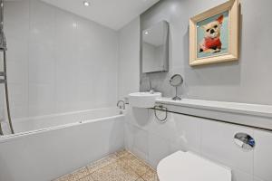 a white bathroom with a dog painting on the wall at Sleek 2BD Flat wTerrace - 2 Mins from Farringdon! in London