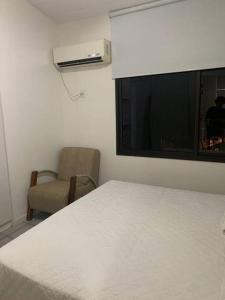 um quarto com uma cama, uma cadeira e uma janela em Itacimirim Villas da Praia em Camassari