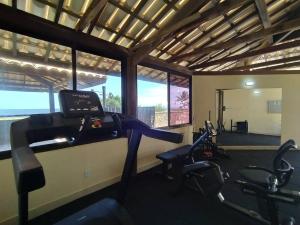 a gym with cardio equipment in a room with windows at Itacimirim Villas da Praia in Camacari