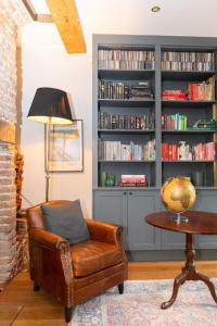 a leather chair in a living room with a book shelf at Elegant & Modern 5BD Home w Garden - Greenwich! in London