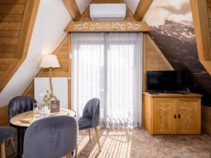 a living room with a table and a tv and a window at Apartamenty Małe Ciche in Małe Ciche