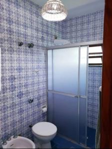 a bathroom with a toilet and a glass shower door at Conforto de casa de campo, ao lado da praia ! in Guarujá