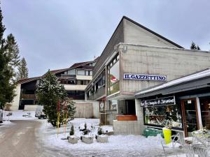 皮恩卡瓦羅的住宿－Piancavallo Panoramica，商店前的地面上积雪的建筑物