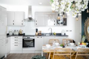 eine Küche mit weißen Schränken und einem Tisch mit Stühlen in der Unterkunft Gloucester getaway with gaming room, desk & parking in Gloucester