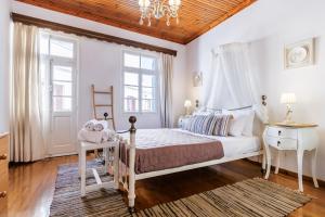 a white bedroom with a bed and a chandelier at villa Yiannoula in Skopelos Town