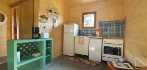 una cocina con electrodomésticos blancos en una cabaña de madera en Pavillon de la biche, en Commensacq