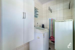 ein weißes Badezimmer mit einem Waschbecken und einem Kühlschrank in der Unterkunft Casa com 05 dormitórios ideal as férias na praia in Canto Grande + 48 Fotos