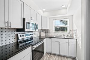 a white kitchen with white cabinets and a window at Bayshore Home in Tampa