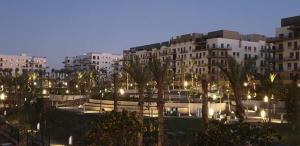 uma cidade à noite com edifícios e palmeiras em Easttown Central Park apartment no Cairo