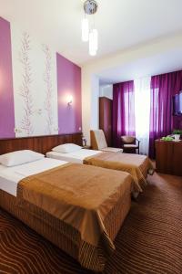ロストフ・ナ・ドヌにあるPark Hotel Nadezhdaの紫の壁のホテルルーム内のベッド2台