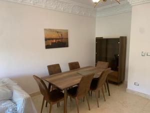 a dining room with a wooden table and chairs at Easttown Central Park apartment in Cairo