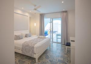 a white bedroom with a bed and a balcony at La Bella Vita Tulum in Tulum