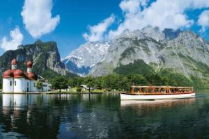 a boat on the water in front of a mountain at NEUES ruhiges Apartment, Bergblick, Stellplatz in Bischofswiesen