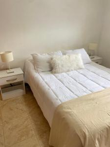 uma cama branca com um edredão branco e uma mesa lateral em Amplio departamento céntrico em Santa Fé