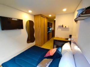 1 dormitorio con 1 cama azul y TV de pantalla plana en Loft Club House Chapinero, en Bogotá