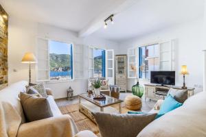 una sala de estar con muebles blancos y ventanas grandes. en villa Yiannoula, en Skopelos Town