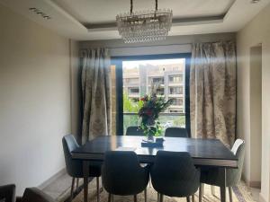 a dining room table with chairs and a window at Serene City Stay next to the AUC, New Cairo in Cairo