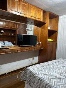 a bedroom with a bed and a desk with a television at Ed Vila de Ofir 200m da Praia in Rio de Janeiro