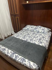a bed with a black and white comforter at Ed Vila de Ofir 200m da Praia in Rio de Janeiro