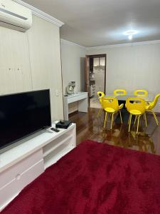 uma sala de estar com cadeiras amarelas e uma televisão de ecrã plano em Ed Vila de Ofir 200m da Praia no Rio de Janeiro