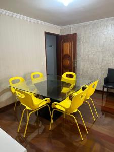 uma sala de jantar com uma mesa de vidro e cadeiras amarelas em Ed Vila de Ofir 200m da Praia no Rio de Janeiro