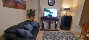 a living room with a black leather couch and a fireplace at OLIVE TREE - 2 Master bedroom (sleeps 6) in Blackpool