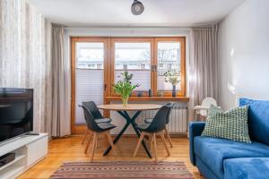 ein Wohnzimmer mit einem blauen Sofa, einem Tisch und Stühlen in der Unterkunft Apartament Lisowski CENTRUM in Zakopane