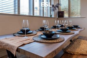 a long wooden table with glasses and plates on it at Stunning 4 bedroom home in Chester