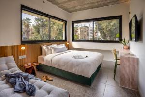 een slaapkamer met een bed, een bank en ramen bij Savanna Dizengoff - Smart Hotel by Loginn Tel Aviv in Tel Aviv