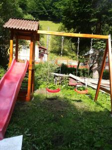 um parque infantil com três baloiços na relva em Căsuța de lângă pădure em Moieciu de Sus