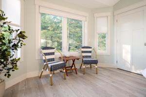 a dining room with two chairs and a table and windows at Relax on Lake Michigan at Tranquil Shores in Norton Shores