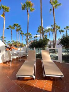 a patio with chairs and a table and palm trees at Sofia23 in Costa Calma