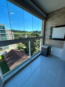 a room with a large window with a view at Apartamento 603, lindo, climatizado, completo in Piratuba