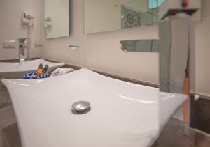 Baño blanco con lavabo y espejo en La Bella Vita Tulum, en Tulum
