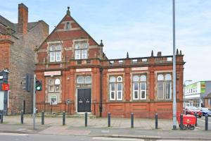 un viejo edificio de ladrillo rojo en una calle de la ciudad en Stay @ The Old Bank Apartments, Burton on Trent, en Burton upon Trent