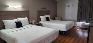 Habitación de hotel con 2 camas con sábanas blancas en Red Lion Inn & Suites Pontoon Beach, en Pontoon Beach