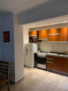 a kitchen with a white refrigerator and wooden cabinets at Complejo Pampa 2 in Santa Rosa