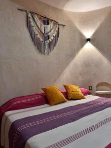 a bedroom with a bed with yellow and purple pillows at Finca Oz in Homún