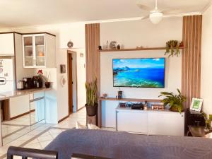 uma sala de estar com uma televisão de ecrã plano na parede em Apartamento Santinho em Florianópolis