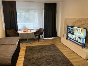 een woonkamer met een tv en een tafel in een kamer bij Gemütliche und entspannte Stadtoase in Krefeld Zentrum, Deluxe Living, 50qm nähe Düsseldorf Messe, Netflix und IpTv in Krefeld