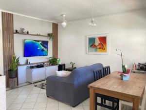 uma sala de estar com um sofá azul e uma mesa em Apartamento Santinho em Florianópolis