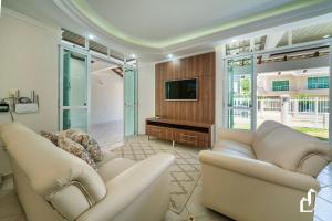 ein Wohnzimmer mit zwei Sofas und einem Flachbildfernseher in der Unterkunft Casa com 05 dormitórios ideal as férias na praia in Canto Grande