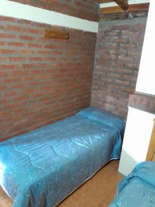 2 camas en una habitación con una pared de ladrillo en DEPARTAMENTOS FORTIN en Trevelín