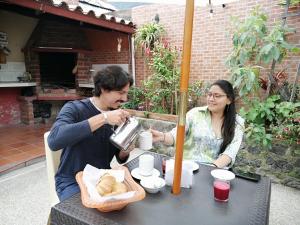 un hombre y una mujer sentados en una mesa con comida en Casa y Flores en Baños