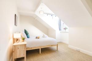 um quarto com uma cama branca num sótão em Spacious 5BR House with Garden & Parking - Near Metro em Jesmond