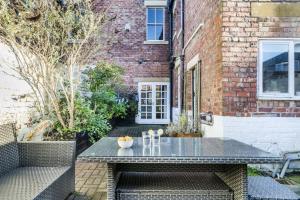 a patio with a table and chairs in front of a brick building at Spacious 5BR House with Garden & Parking - Near Metro in Jesmond