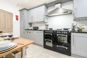 uma cozinha com electrodomésticos pretos e uma mesa de madeira em Spacious 5BR House with Garden & Parking - Near Metro em Jesmond