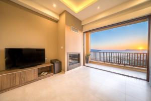 a living room with a flat screen tv and a large window at Golden View Luxury Villa Platanias in Platanias