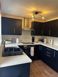 a kitchen with black cabinets and white counter tops at Ripon House in Dallington