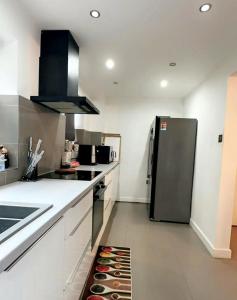 uma cozinha com um frigorífico preto e armários brancos em Cosy and Unique Bedroom In Gateshead em Sheriff Hill